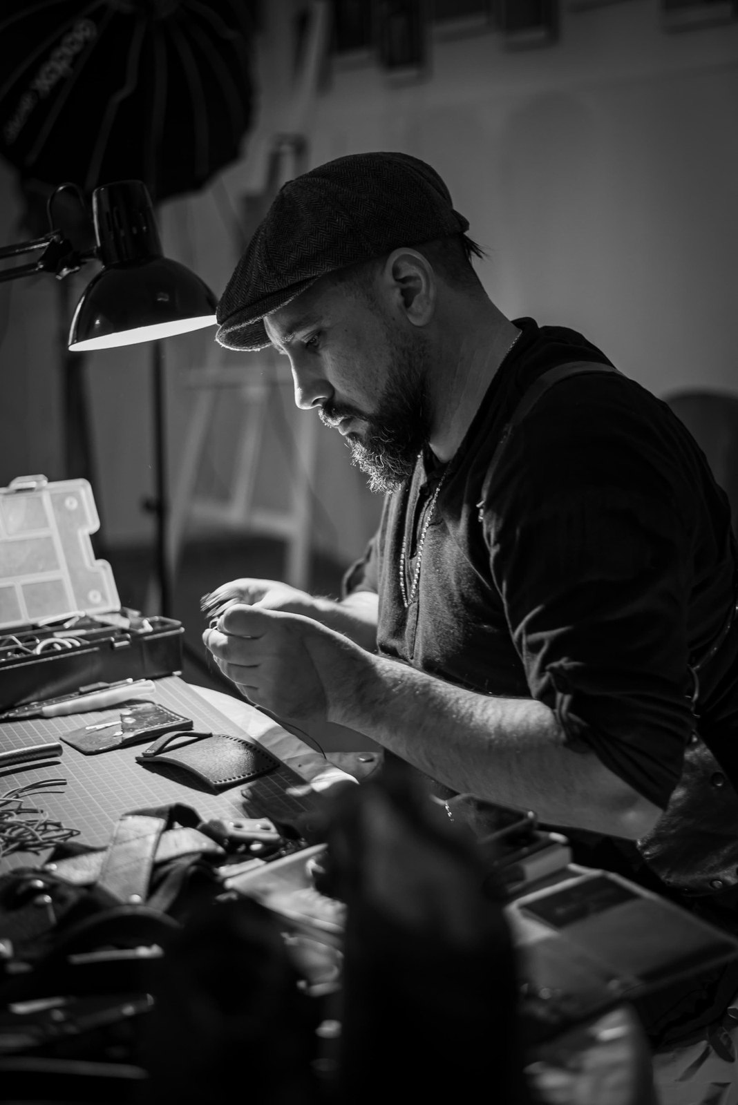 Jonatan, de Proyecto Design, cosiendo a mano una pieza de cuero en su mesa de trabajo
