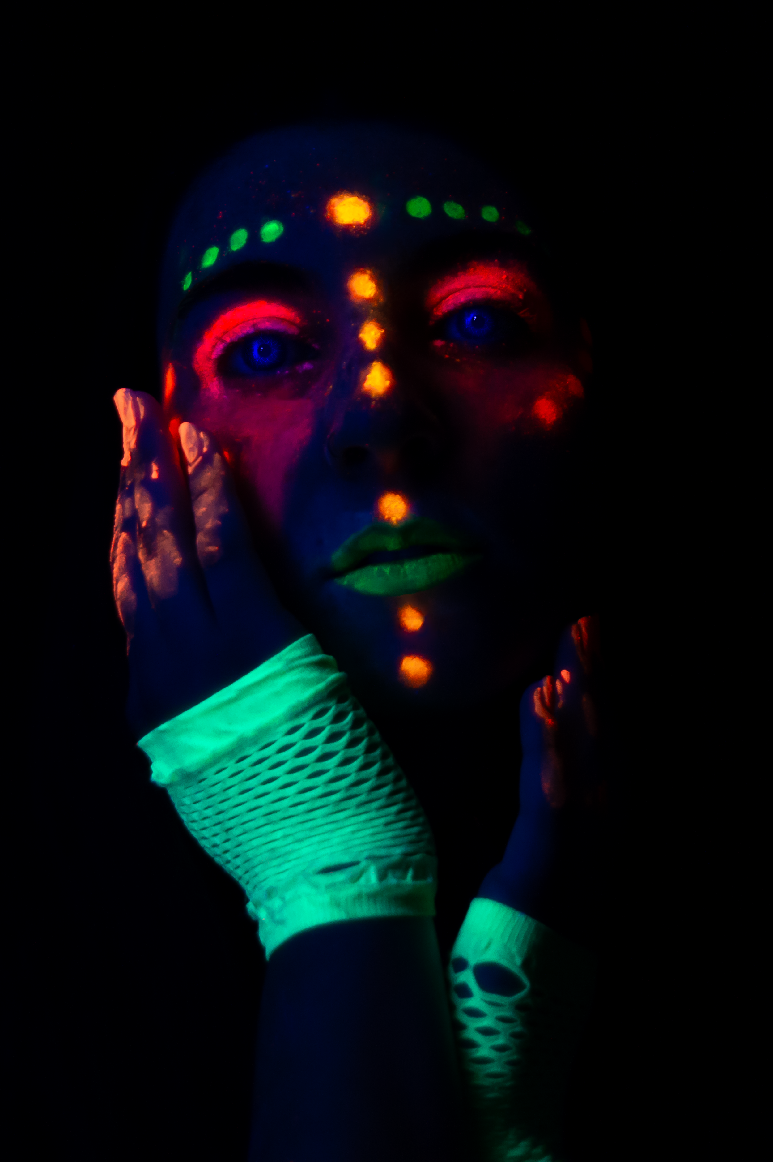 Retrato artístico de un rostro iluminado por puntos fluorescentes verdes, azules y rojos, que contrastan con el fondo oscuro. Rosario.