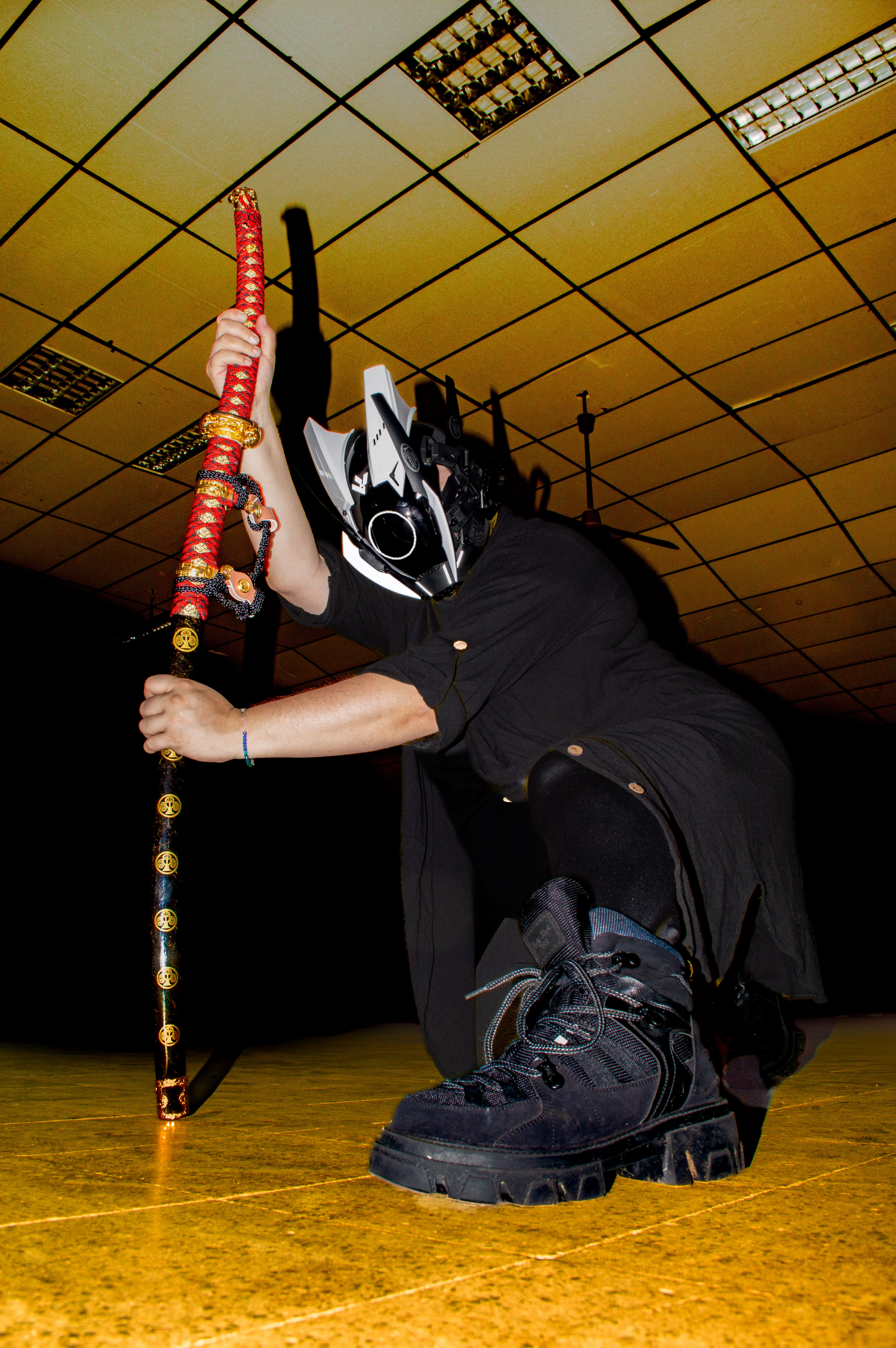 Cosplay futurista, vistiendo casco con luces y sosteniendo un arma en pose de combate.