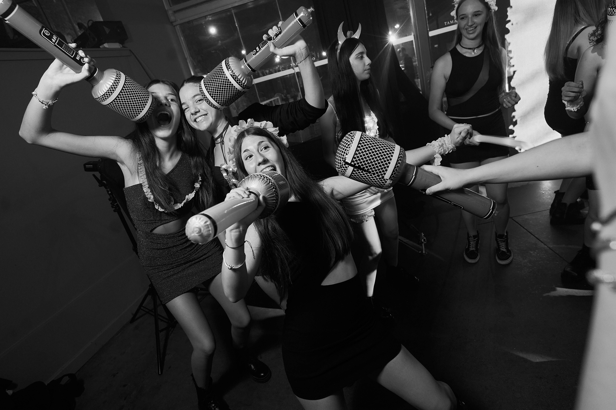 Amigas cantando con micrófonos inflables en la pista, en blanco y negro. Carioca de una fiesta de 15 fotografiada por DNX Estudio, Funes.