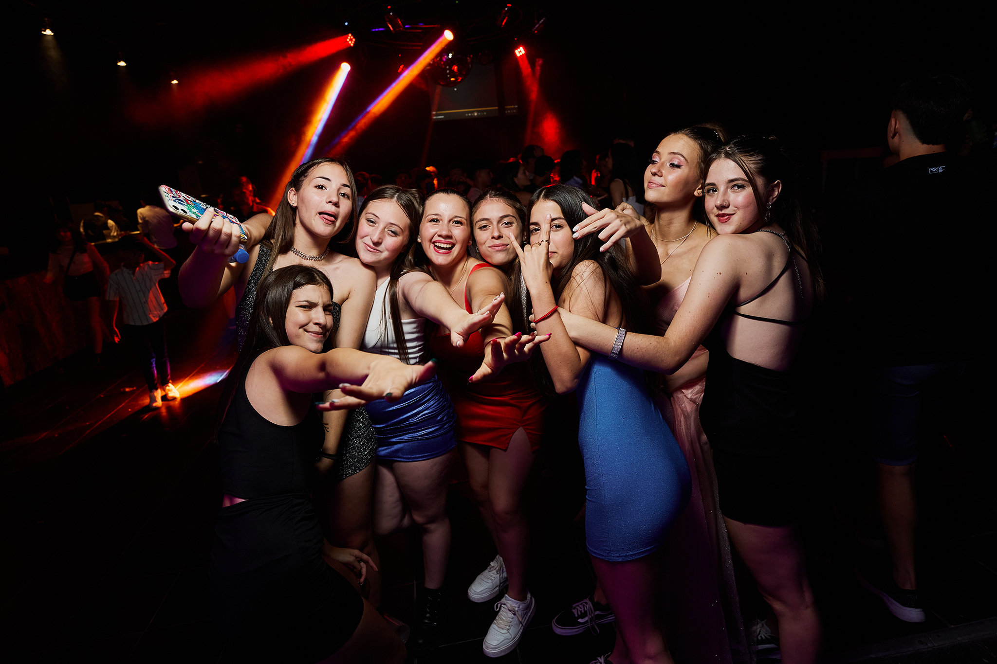 Ocho amigas posando juntas en la pista, bajo luces rojas y azules. Cobertura de fiesta de 15 de Daniel Cuart, DNX Estudio, Funes, Rosario.