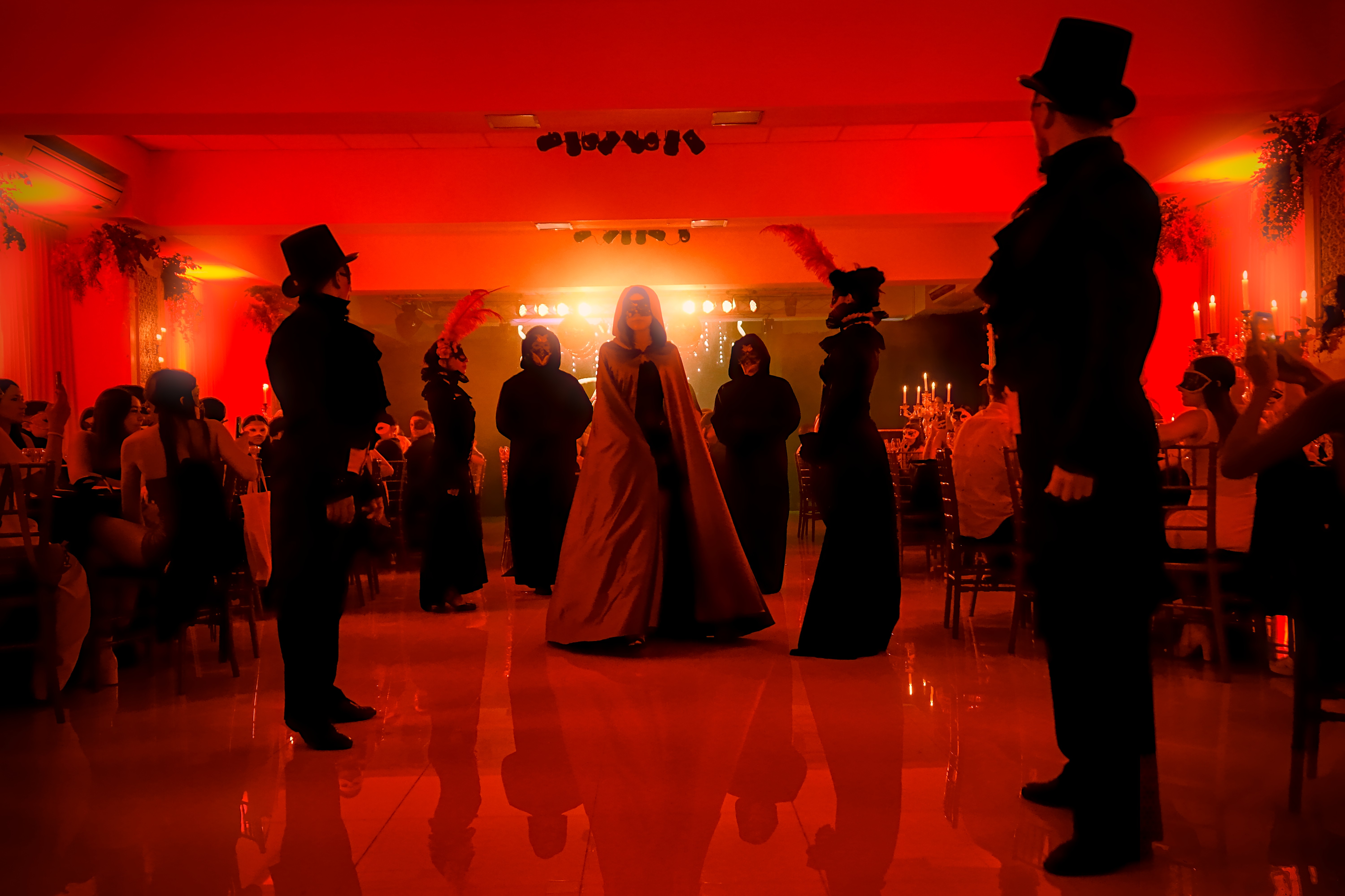 Entrada de la cumpleañera en fiesta de 15 años temática de máscaras y antifaces con invitados en salón.